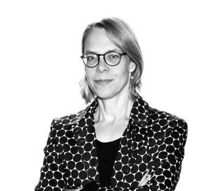 Schwarzweißbild einer blonden Frau mit Brille in gemusterten Blazer 